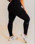 Person wearing a black athletic outfit with visible branding on a plain background