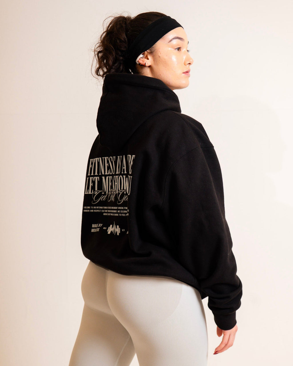 Person wearing a black hoodie with text on the back against a plain background