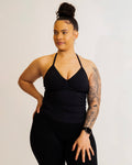 Woman wearing a black tank top and leggings on a plain background
